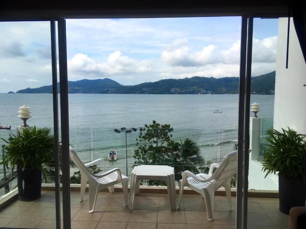 a table and chairs on a balcony with a view of the water at The Front Hotel and Apartments in Patong Beach