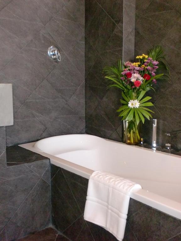 a bathroom with a white bath tub with a vase of flowers at The Front Hotel and Apartments in Patong Beach