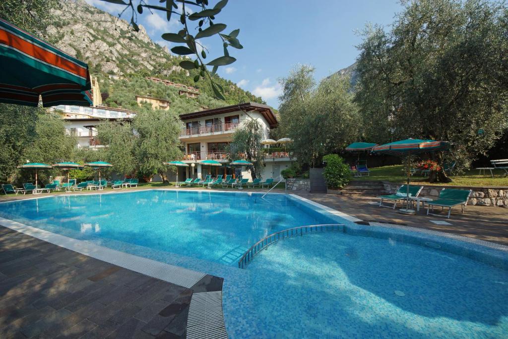 una grande piscina blu con un hotel sullo sfondo di Hotel Coste a Limone sul Garda