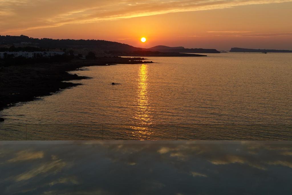 a sunset over a body of water with the sun setting at Can Salia in San Antonio Bay