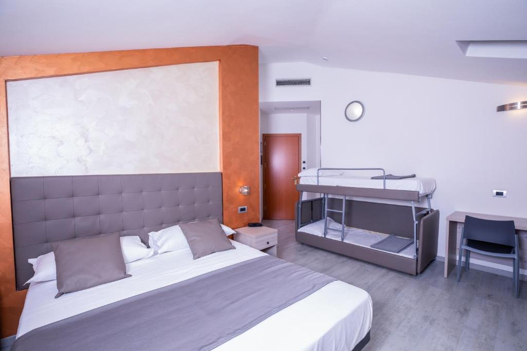a bedroom with a large bed and a desk at Hotel Gabbiano in Rimini