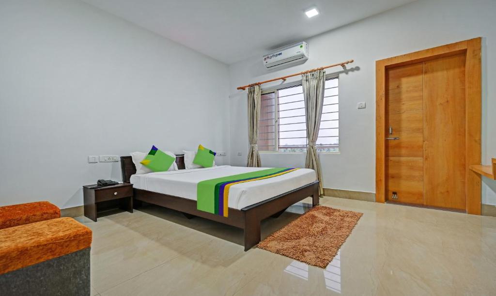 a bedroom with a bed and a wooden door at Treebo Trend Sidhartha Inn Baliapanda in Puri