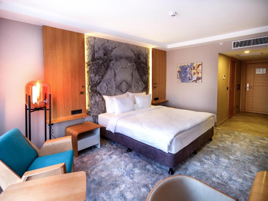 une chambre d'hôtel avec un grand lit et des chaises dans l'établissement Grande Arte Hotel, à Eskişehir