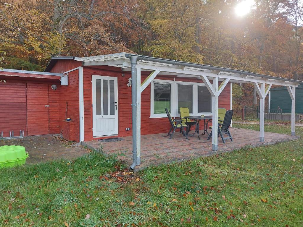 een rood huis met een patio met een tafel en stoelen bij Bungalow Waldblick in Ganzlin