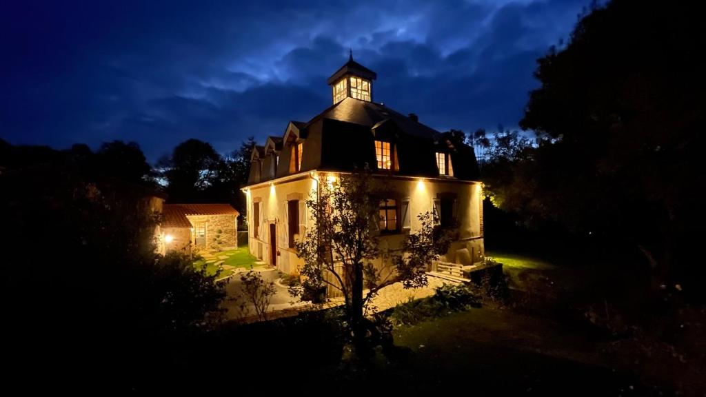 an old building with a clock tower on top at night at La Demoiselle de Bohardy in Montrevault