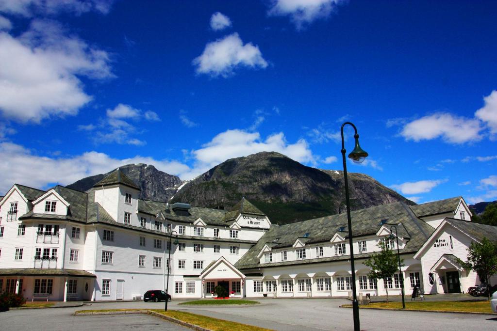 um grande edifício branco com uma montanha ao fundo em Vøringfoss Hotel em Eidfjord