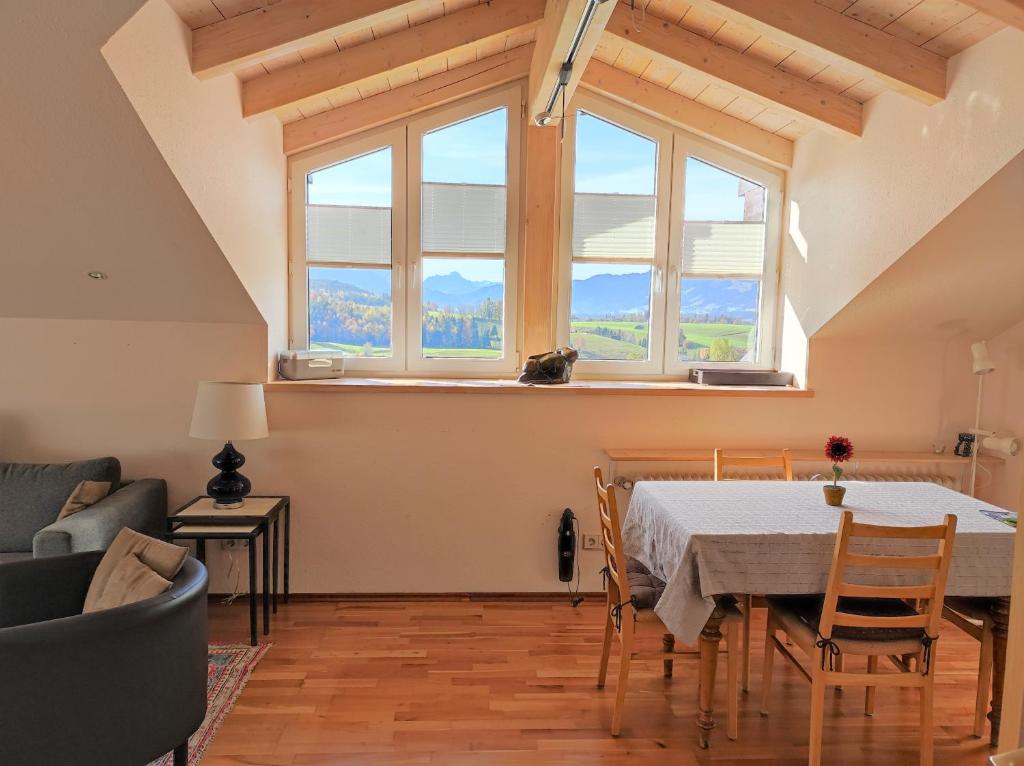 ein Wohnzimmer mit einem Tisch, Stühlen und einem Fenster in der Unterkunft Ferienwohnung Imberger Horn - Sonthofen in Sonthofen