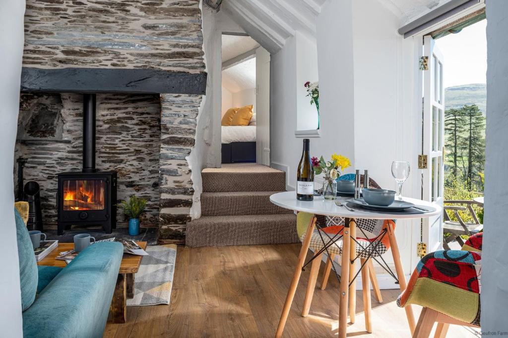 uma sala de estar com uma mesa e uma lareira em The Little Cottage em Bryn-crug