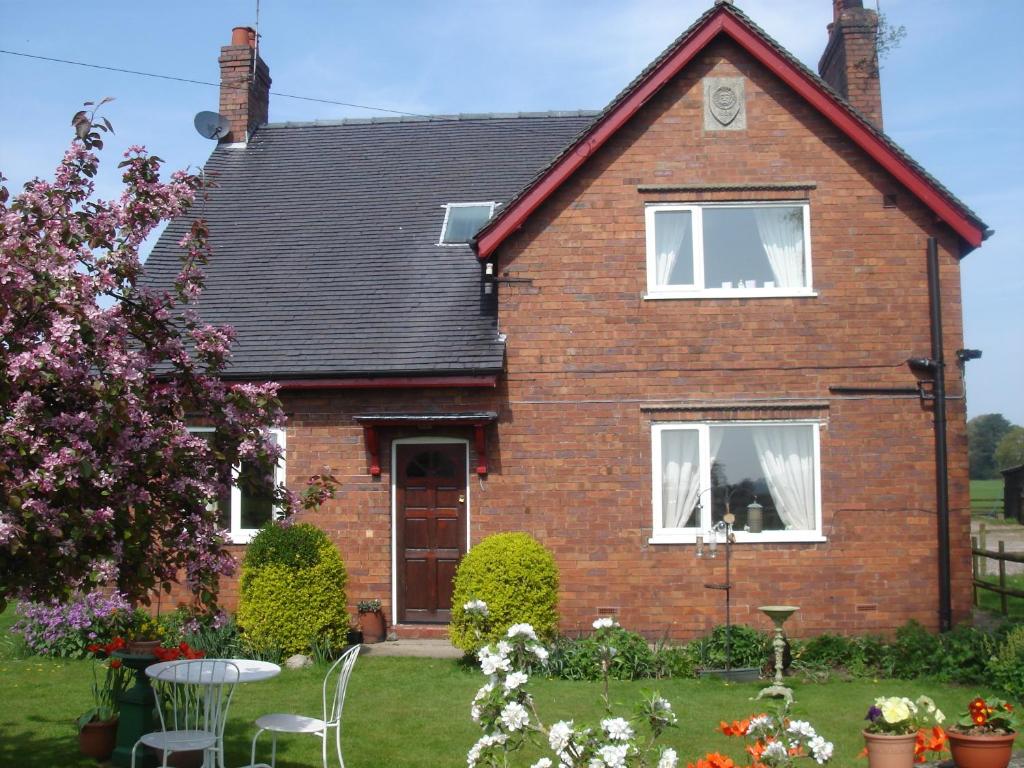 una casa de ladrillo rojo con un patio de hierba en Yew Tree Farm en Congleton