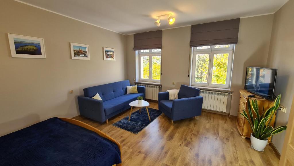 a living room with two blue chairs and a tv at Apartament Parkowy Piątka in Gniezno