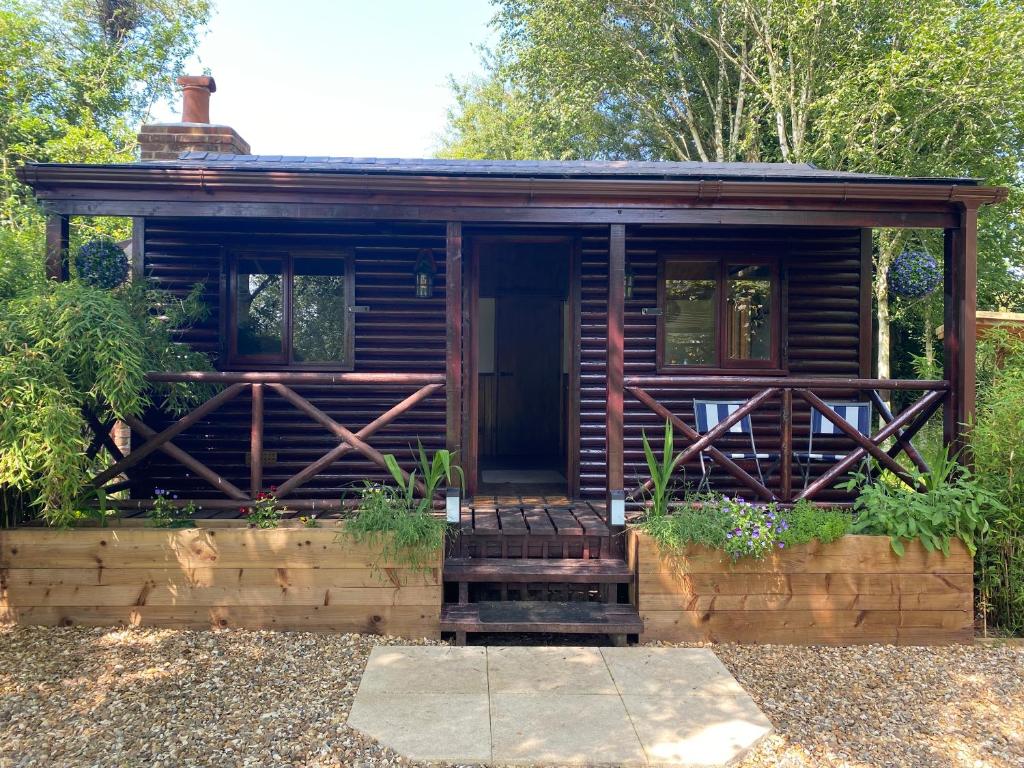 a log cabin in a garden with a porch at Luxury Log Cabin with Outdoor Wood Fired Hot Tub & Pizza Oven in Ribchester