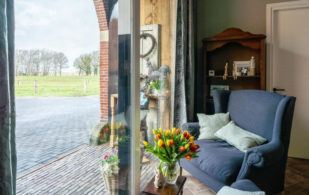 a living room with a blue couch and a vase of flowers at B&B Erve Groot Wegereef in Hengevelde