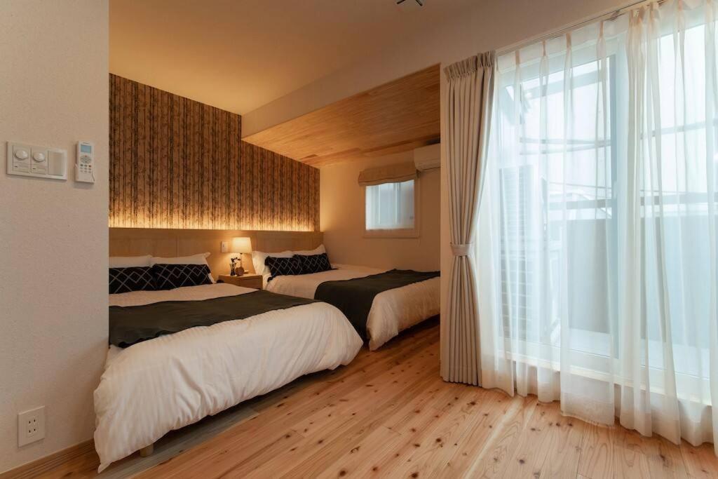 1 dormitorio con 2 camas y ventana grande en OCHANOMA en Ebisuchō