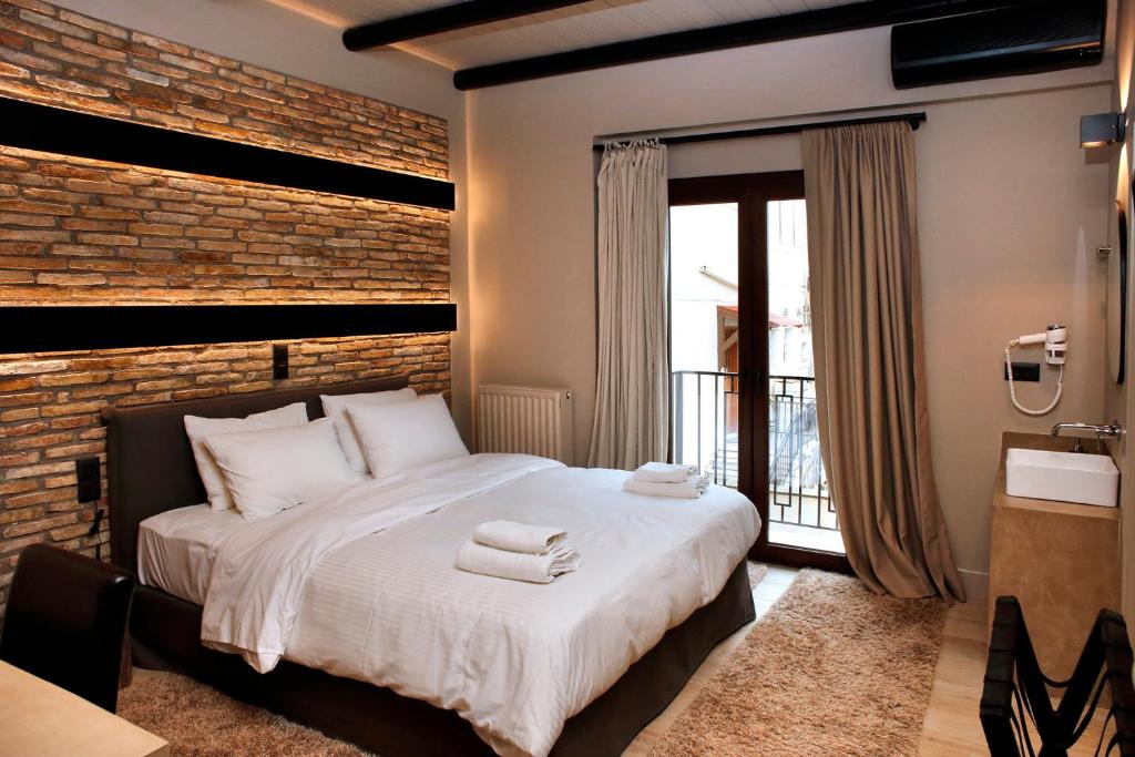 1 dormitorio con 1 cama grande y pared de ladrillo en Anesis Hotel, en Kalavrita