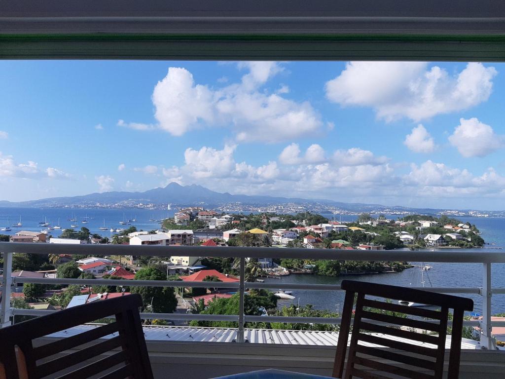 - un balcon avec deux chaises offrant une vue sur la ville dans l'établissement akate, à Les Trois-Îlets