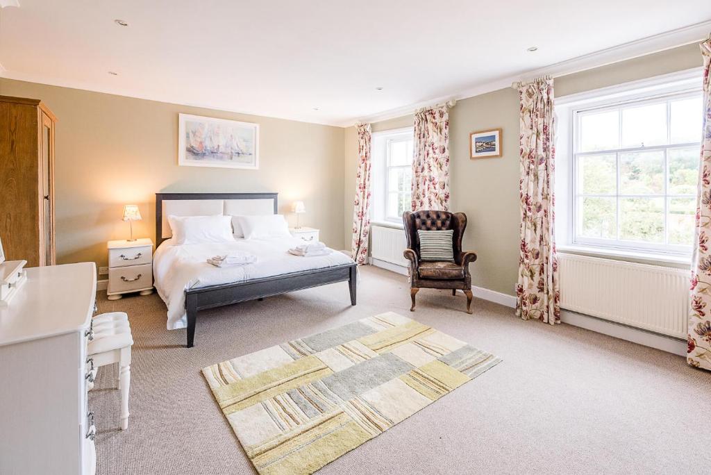 een slaapkamer met een bed, een stoel en ramen bij 4 Market Cross House Aldeburgh Air Manage Suffolk in Aldeburgh