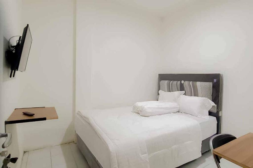 um quarto branco com uma cama com lençóis e almofadas brancos em Maminoti Syariah Residence Mitra RedDoorz em Bogor