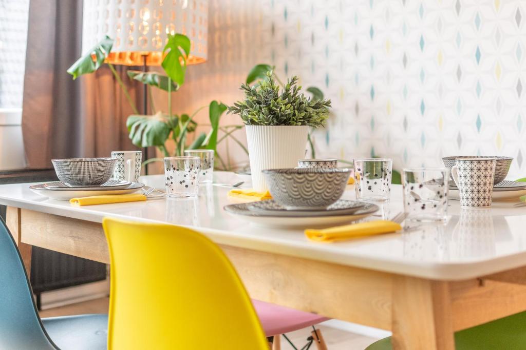 een witte tafel met gele stoelen en een tafel met borden en glazen bij VilvoCity Center in Vilvoorde
