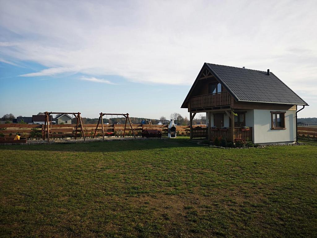 una pequeña casa en un campo con parque infantil en Domek u Lipków na Kaszubach "Iga" JACUZZI en Lipusz