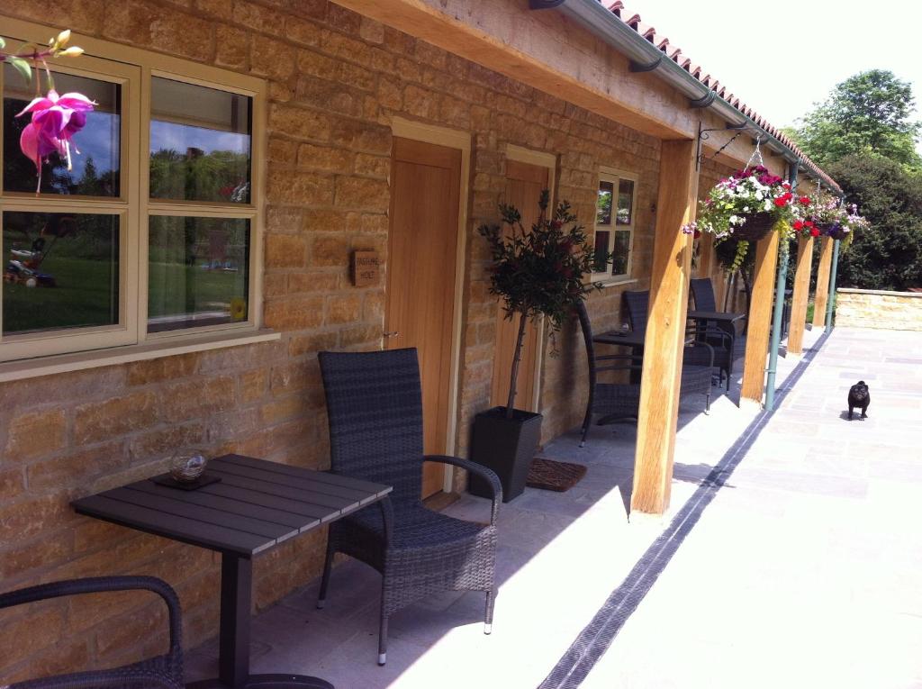 um pátio com uma mesa e cadeiras numa casa em The Cholmeley Arms em Burton Coggles