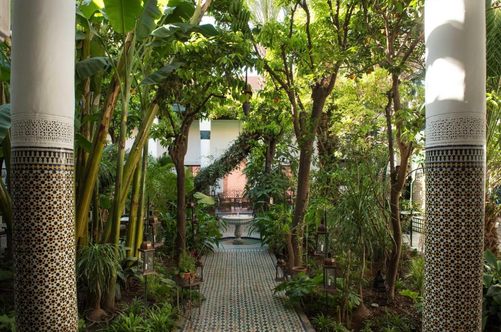 einen Gehweg durch einen Garten mit Bäumen und Pflanzen in der Unterkunft Palais Riad Lamrani in Marrakesch