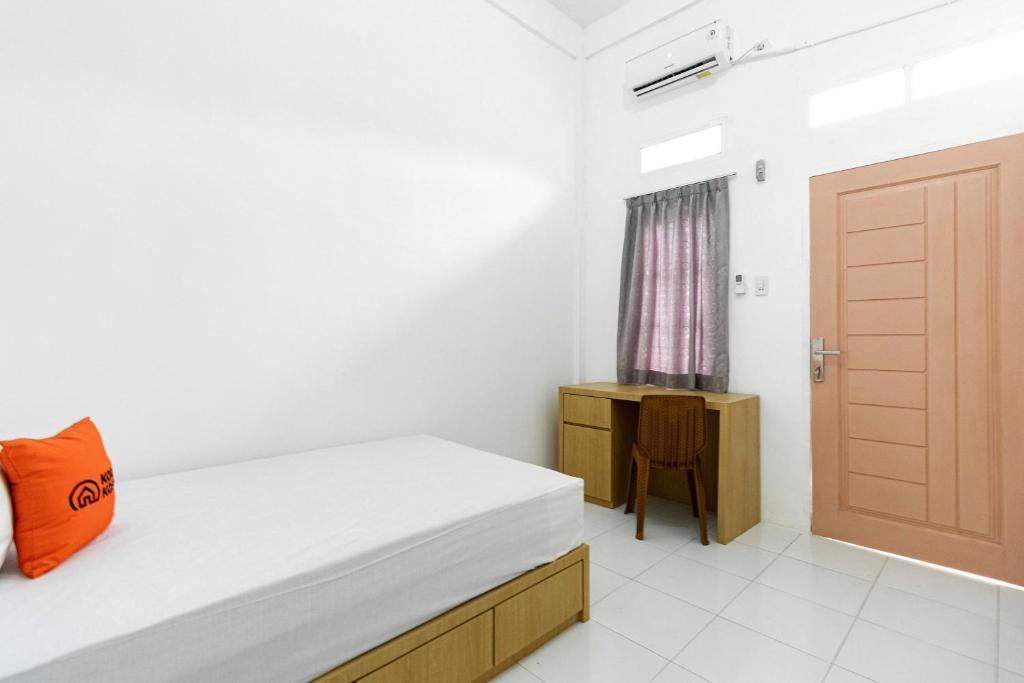 een slaapkamer met een bed, een deur en een tafel bij KoolKost At Jalan Ciheulang Bandung - Minimum Stay 30 Night in Bandung