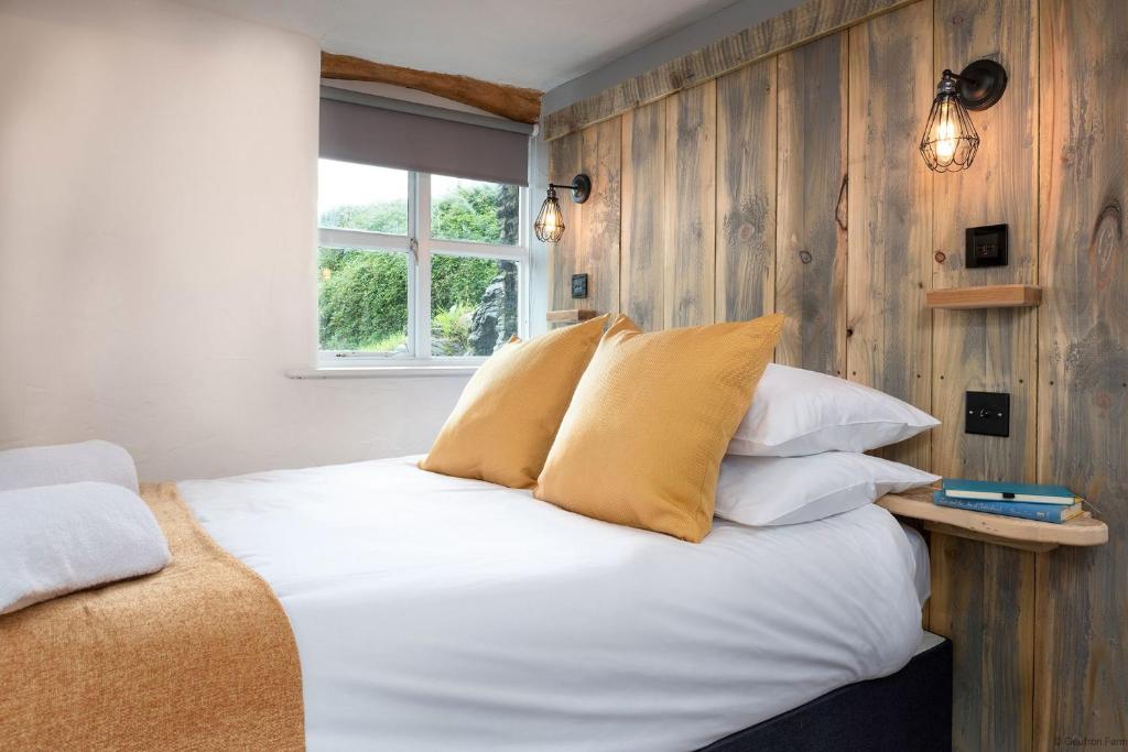 um quarto com uma cama com lençóis brancos e almofadas amarelas em The Granary em Bryn-crug
