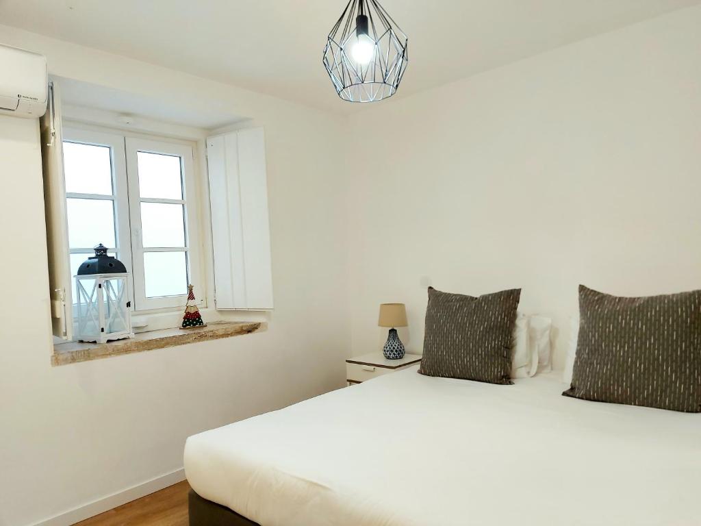 a white bedroom with a bed and a window at Residenza Dutzu - Aparthotel Leiria in Leiria