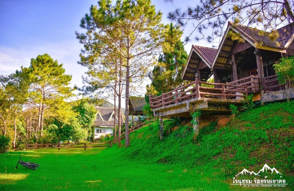 een huis op een heuvel met groen gras en bomen bij ไร่นุชชม รีสอร์ทเขาค้อ in Ban Non Na Yao