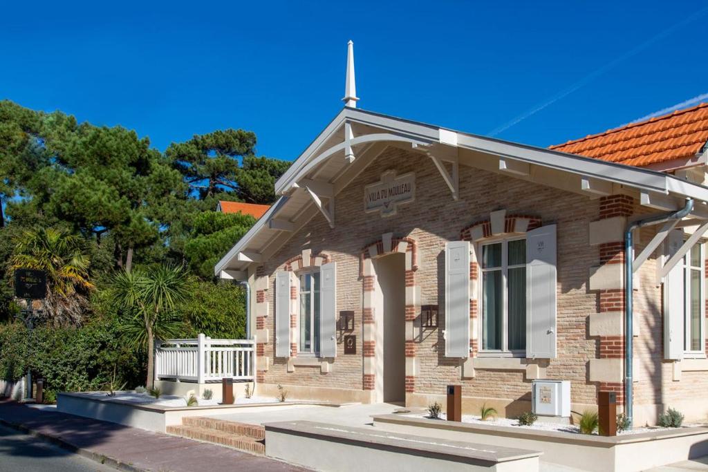 an old brick house with a white fence at La Villa du Moulleau in Arcachon