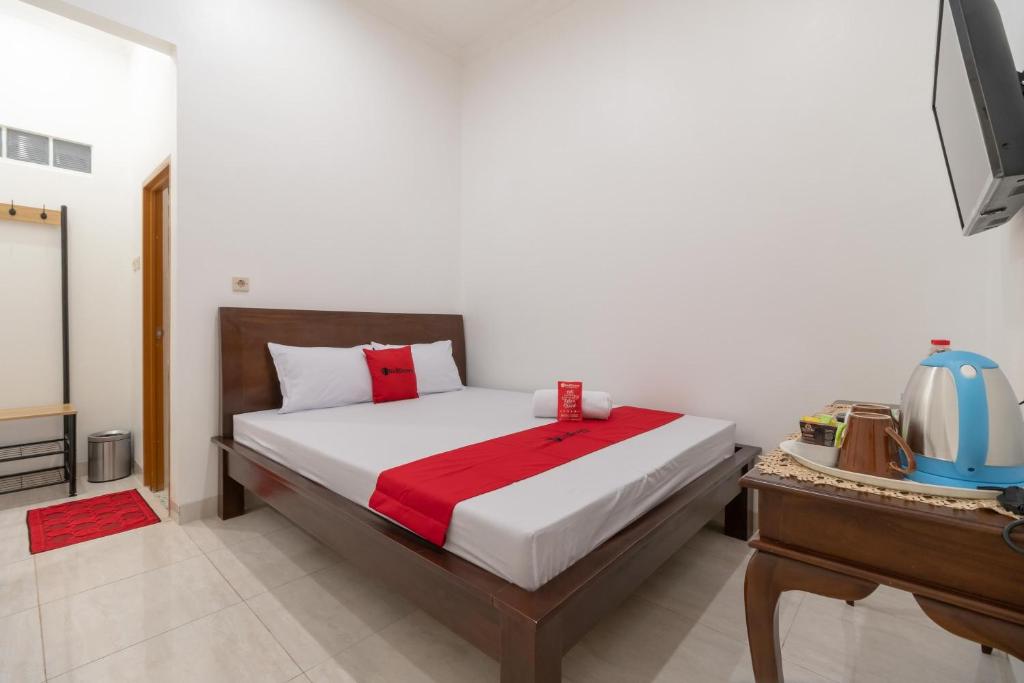 Dormitorio con cama, escritorio y TV en RedDoorz Syariah near Summarecon Mall Bekasi en Kayuringin
