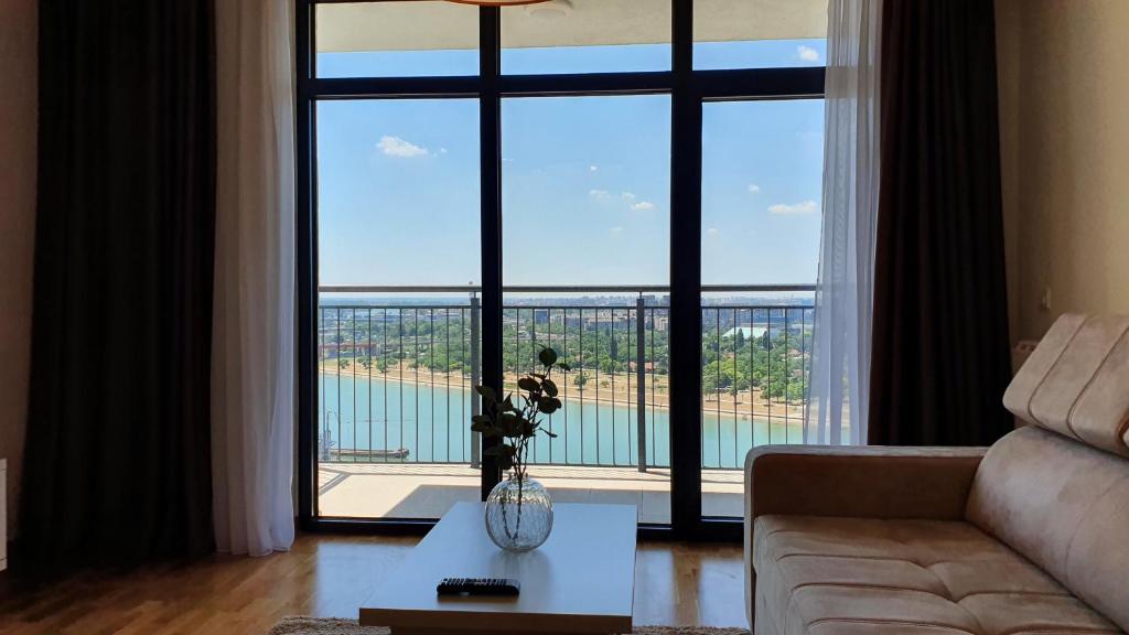 a living room with a couch and a large window at Beograd na vodi - Belgrade Waterfront Riverside in Belgrade