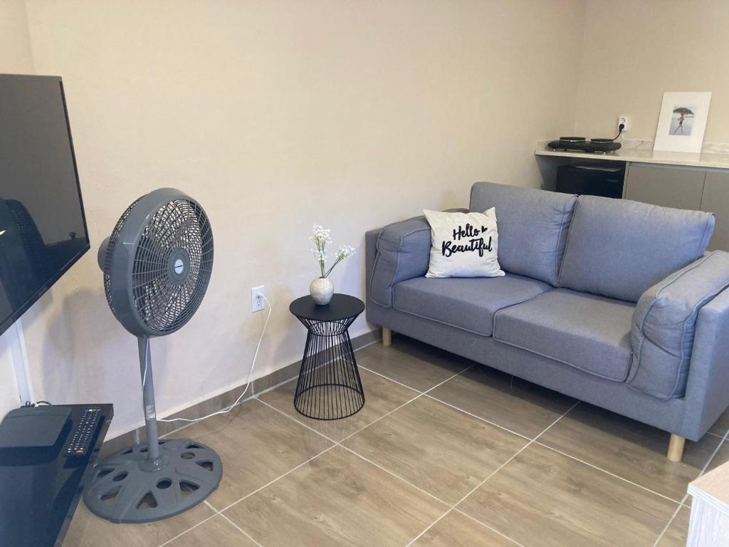 a living room with a blue couch and a fan at Place2cu-Studio apartment in Willemstad