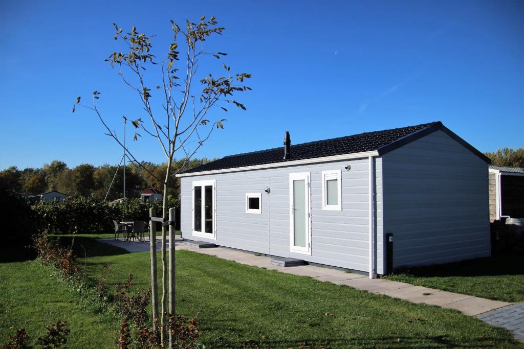 a white shed with a black roof in a yard at Chalet Landlust in Drijber