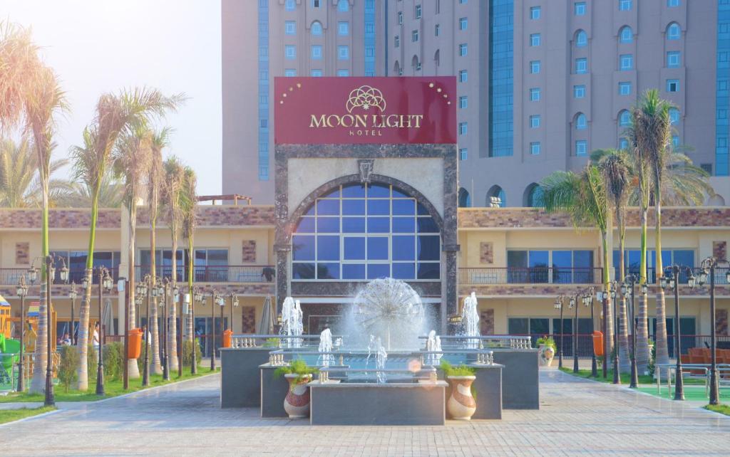 une fontaine en face d'un bâtiment avec des palmiers dans l'établissement Moon Light Hotel Cairo DAR EL ESHARA, au Caire