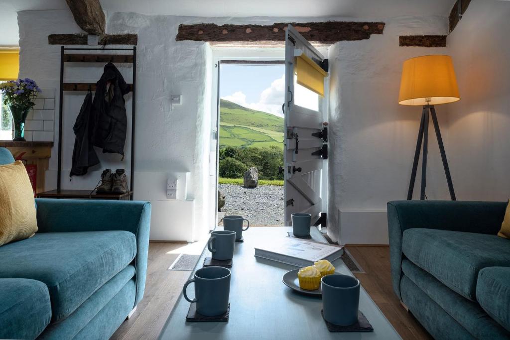 ein Wohnzimmer mit zwei blauen Sofas und einem Fenster in der Unterkunft The Cowshed in Bryn-crug