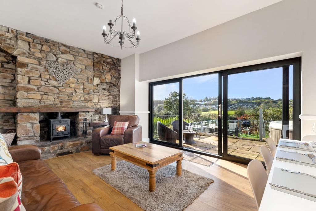 a living room with a stone wall and a fireplace at Cartref - Beautiful Cottage, Hot Tub, Countryside Views in Saundersfoot