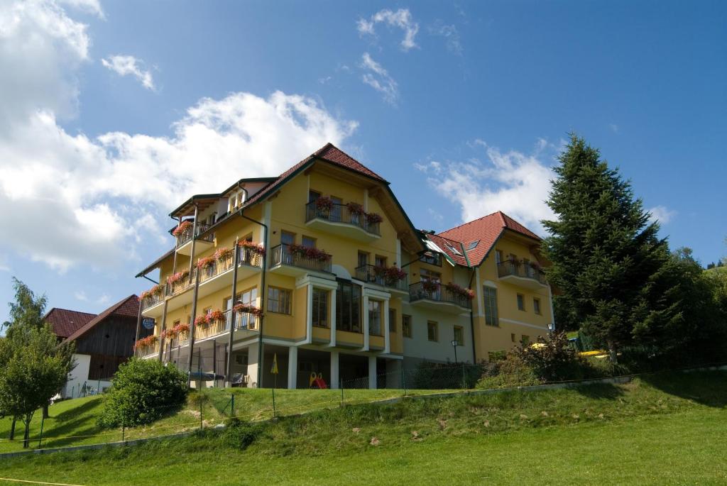 um grande edifício amarelo com varandas numa colina em Wildwiesenhof em Miesenbach