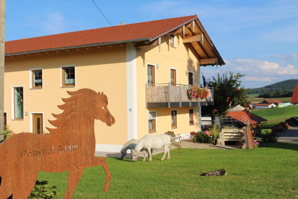 una estatua de un caballo de madera frente a una casa en Ponyhof Adam Urlaub auf dem Bauernhof, en Eschlkam