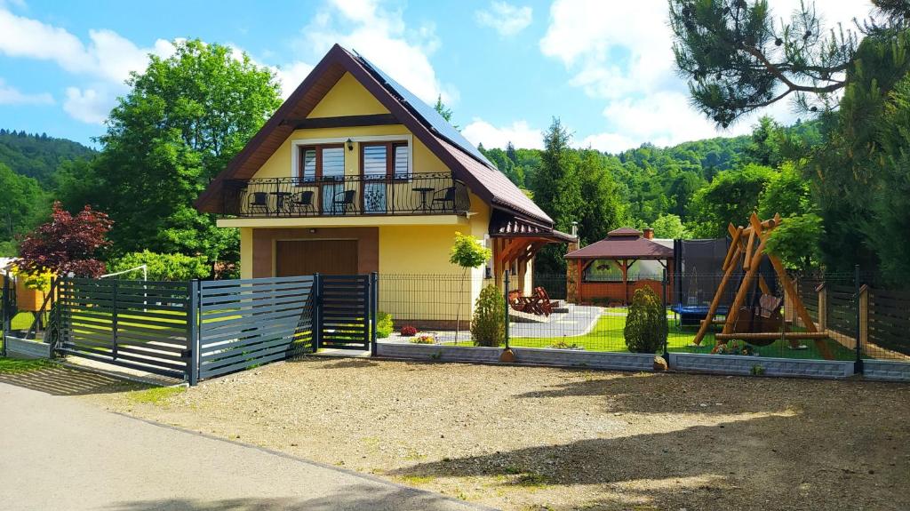 une petite maison avec une clôture et une aire de jeux dans l'établissement Agroturystyka Wilkowyja, à Mchawa