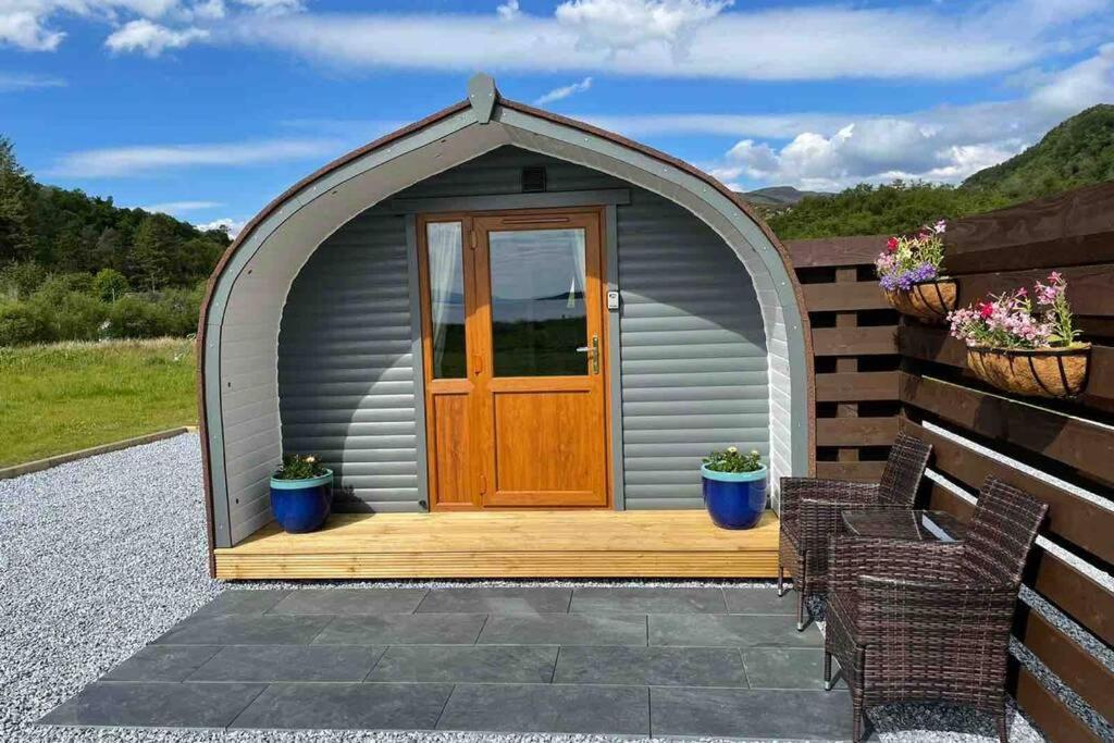 een tuinhuisje met een houten deur op een patio bij Sea Breeze Pod in Fort William