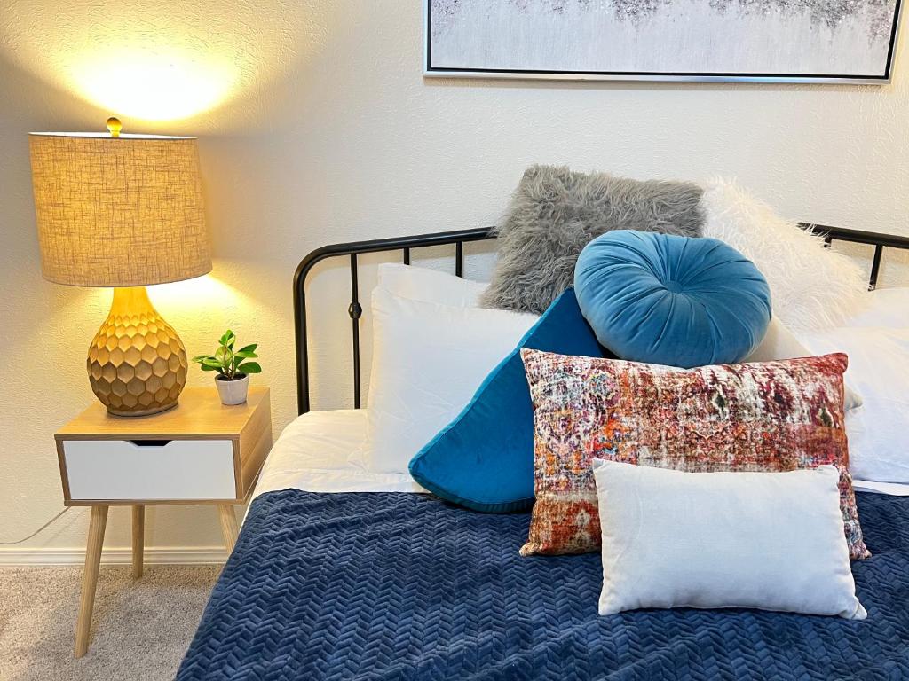 a bedroom with a bed with pillows and a lamp at The Burque Boho House in Albuquerque