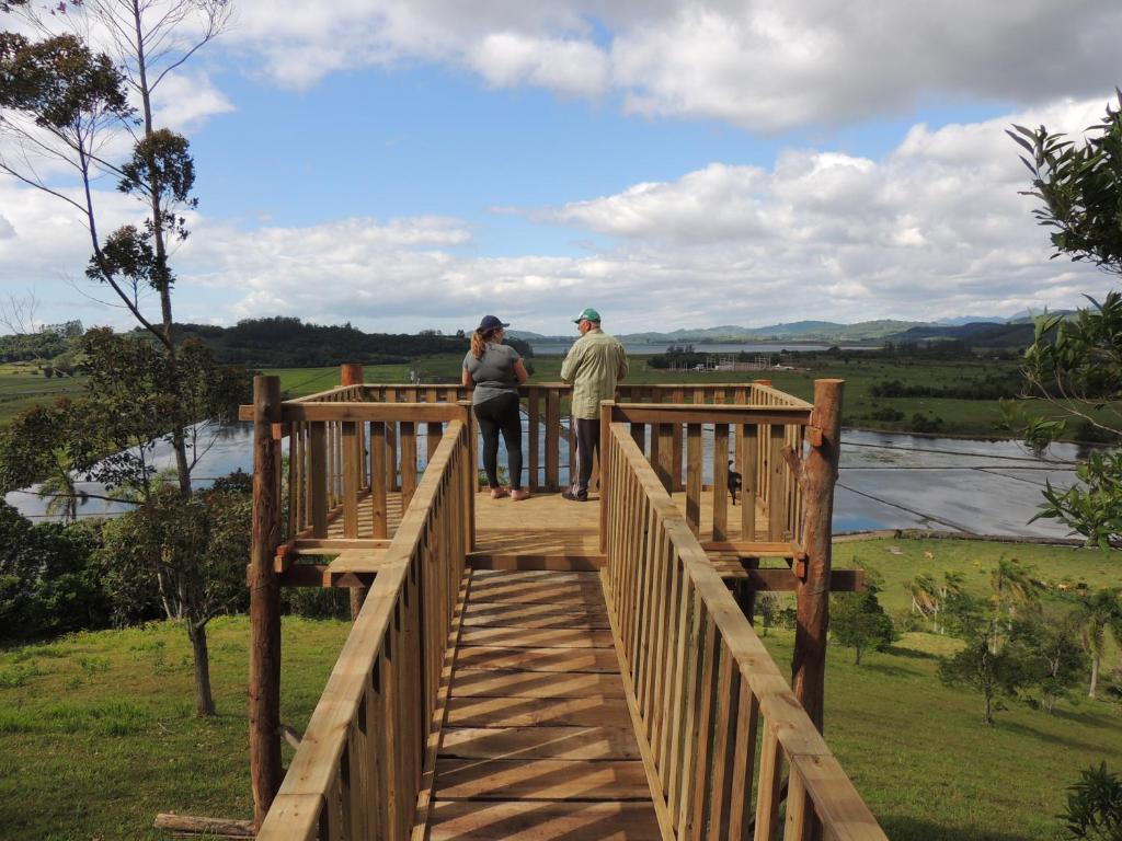dos personas de pie en un puente de madera sobre un río en Sítio Vô Inácio - casa inteira en Torres