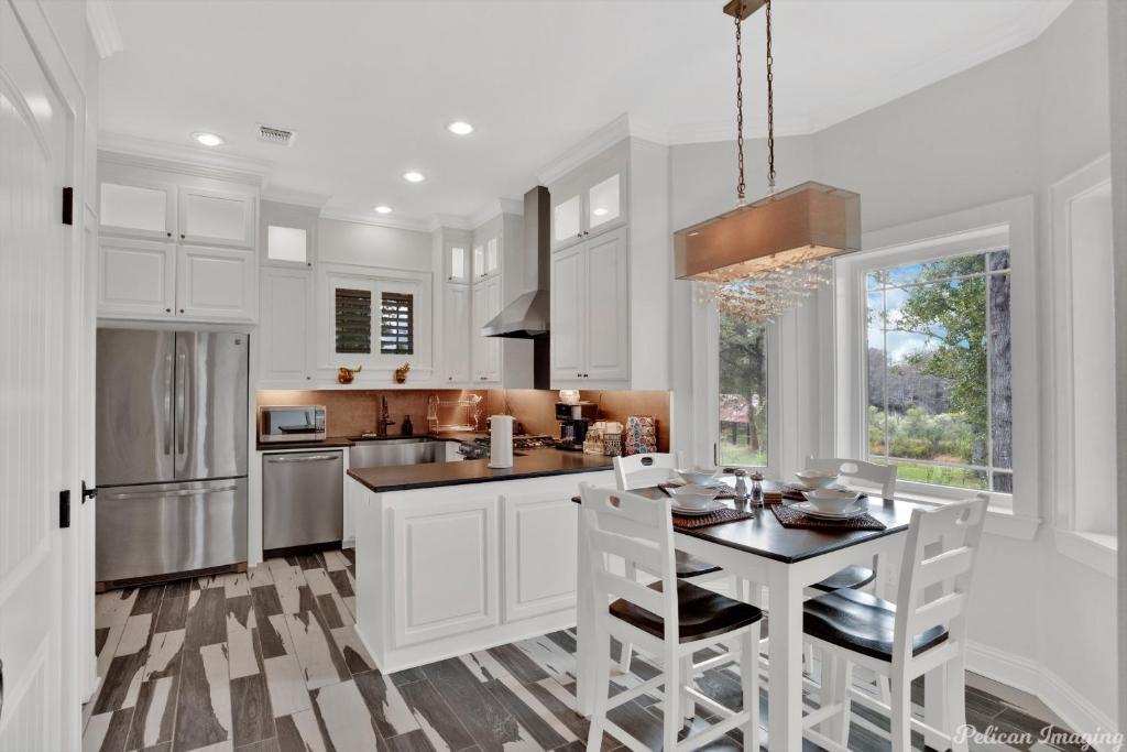 a kitchen with white cabinets and a table with chairs at The Cross Lake Maison in Shreveport