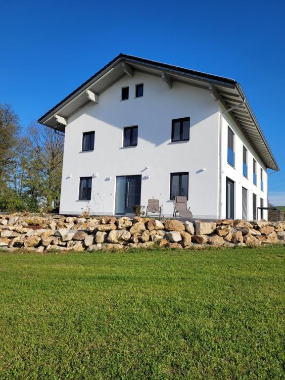 a white house on top of a rock wall at Ferienwohnung Bergmaier in Bad Birnbach