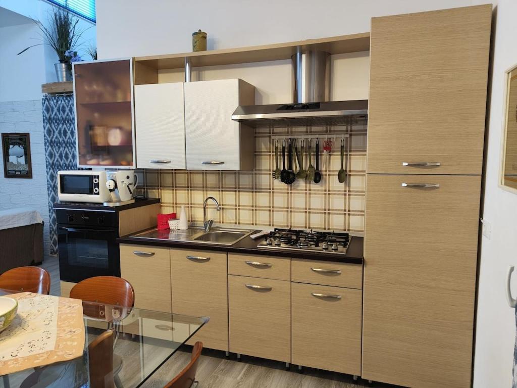 cocina con armarios de madera y mesa de cristal en Alcamo Marina Villa Pool, en Alcamo Marina