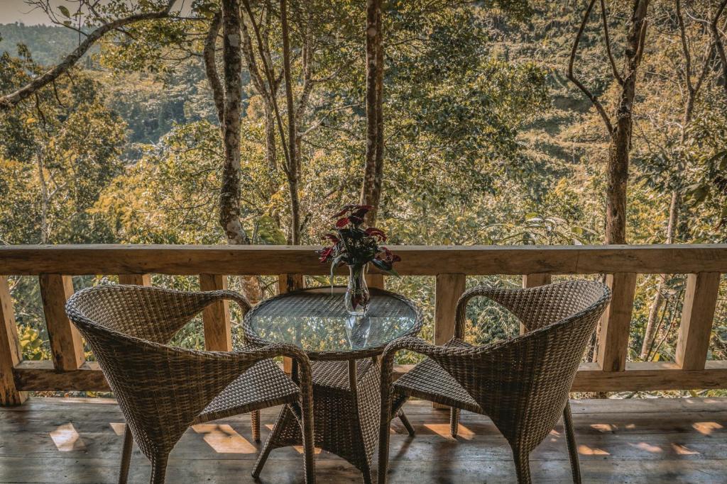 a glass table and chairs on a porch with a view at Gumi Ayu EcoHotel in Munduk