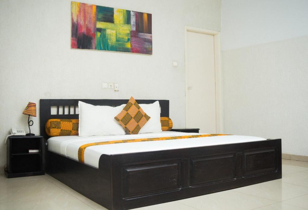 a bed in a bedroom with a painting on the wall at Hôtel Seaside in Lomé