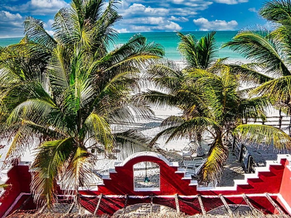 una spiaggia con palme e un edificio rosso sulla sabbia di Beachfront Apartment Hacienda del Cuyo a El Cuyo