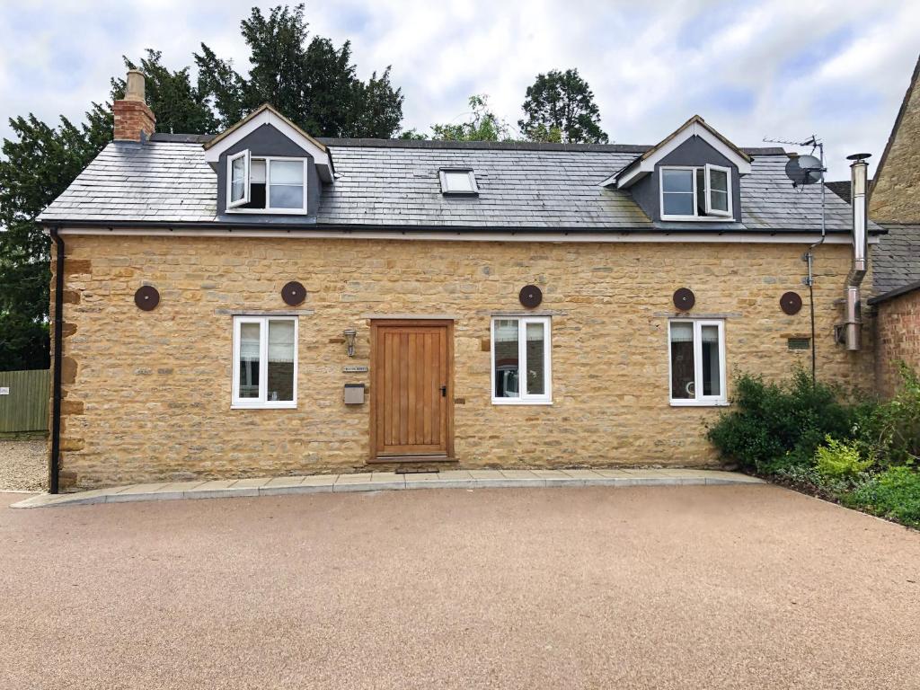 a brick house with a wooden door on a driveway at The Manor Barn in Northampton